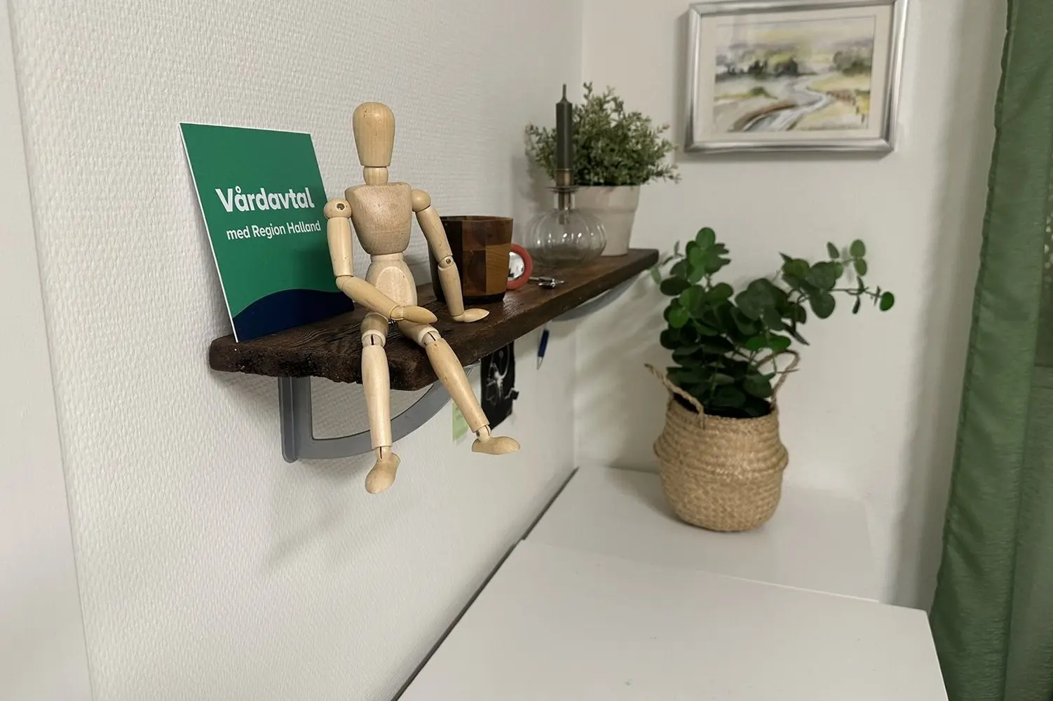 Träfigur på en hylla bredvid skylten Vårdavtal med Region Halland